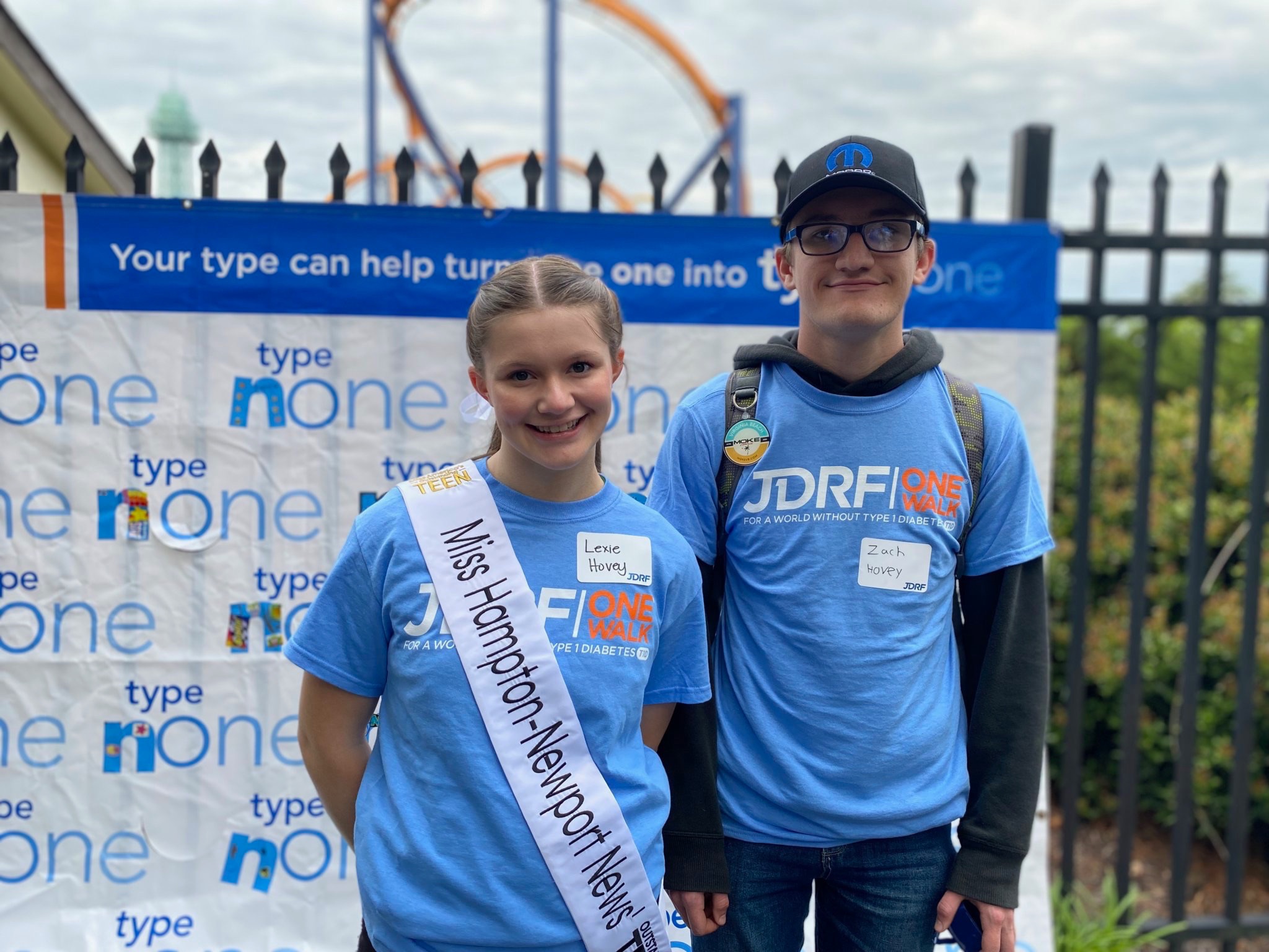 Lexie Hovey and Zach Hovey wearing JDRF One Walk shirts in front of Type None banner
