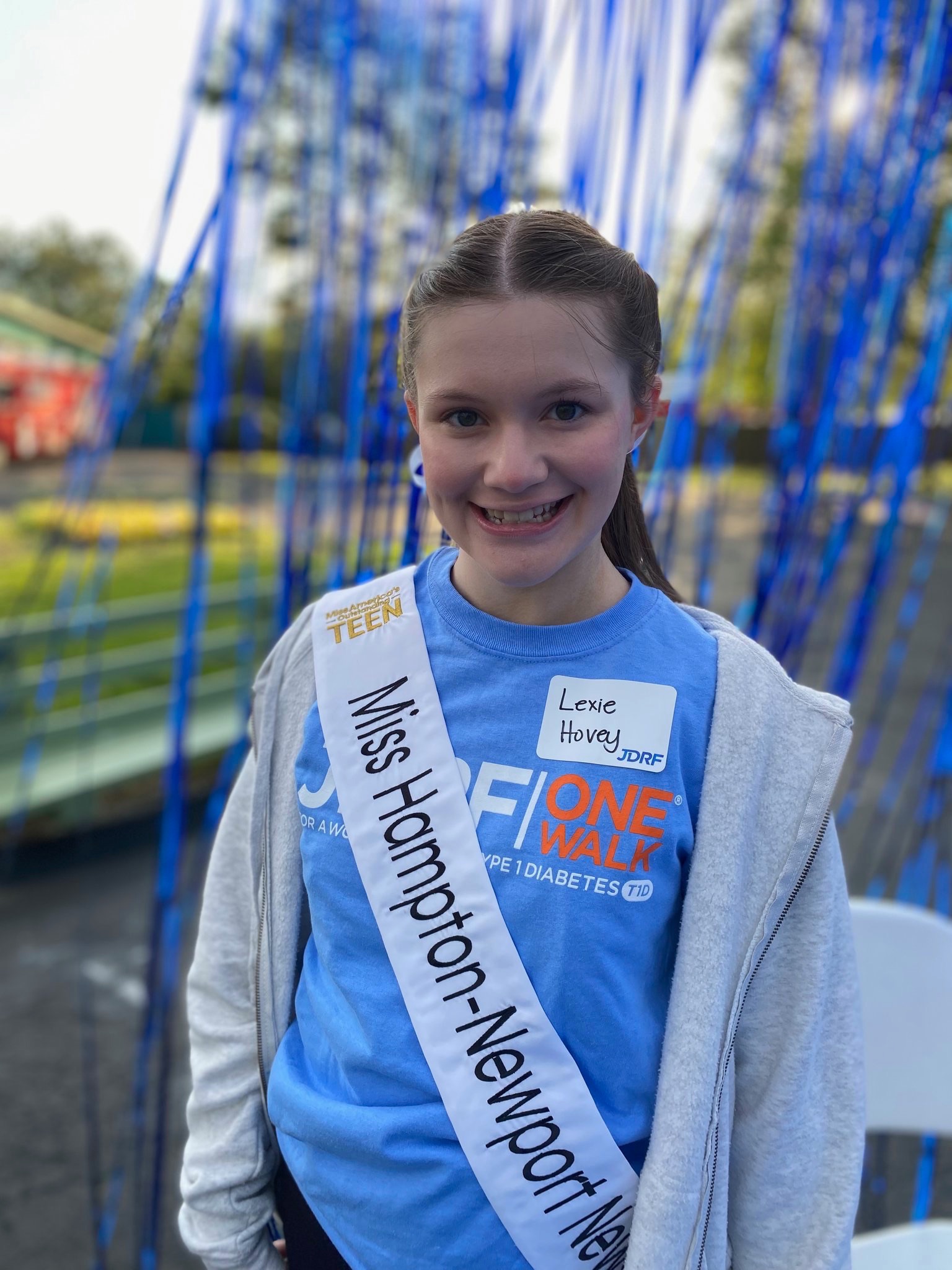 Lexie Hovey wearing Miss Hampton-Newport News sash and JDRF One Walk shirt, smiling at the walk
