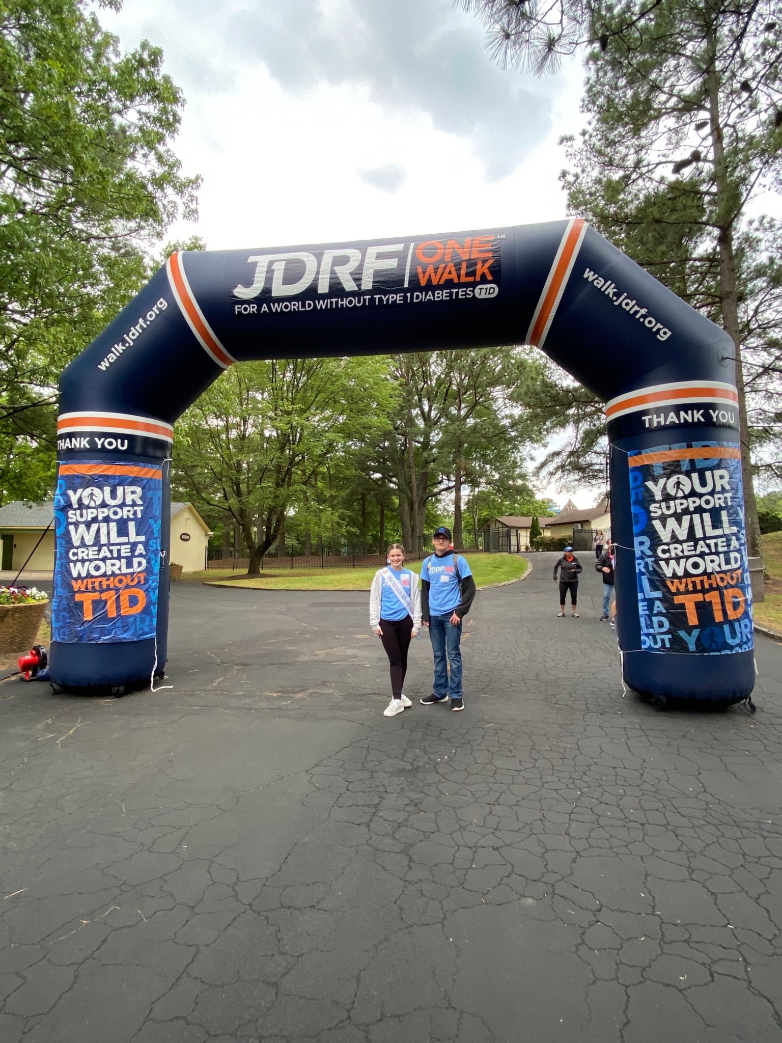 Lexie Hovey and family standing under the JDRF One Walk arch at the walk event