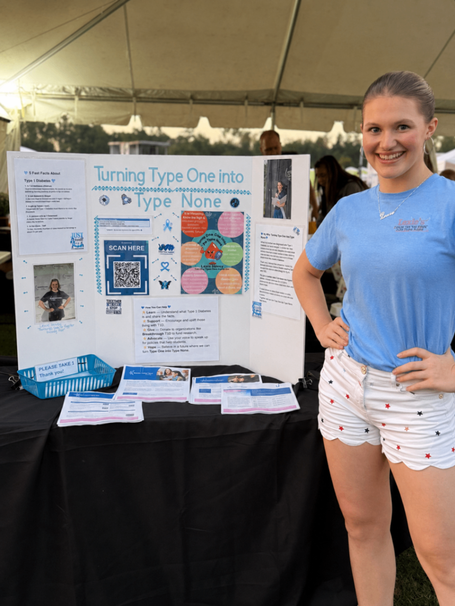 Lexie Hovey standing beside her Turning Type One into Type None display board at a community outreach event